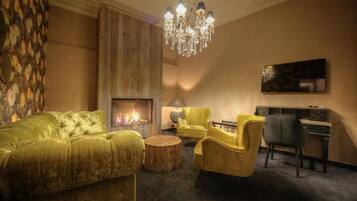 A cozy living room with a fireplace, a chandelier, and comfortable seating.