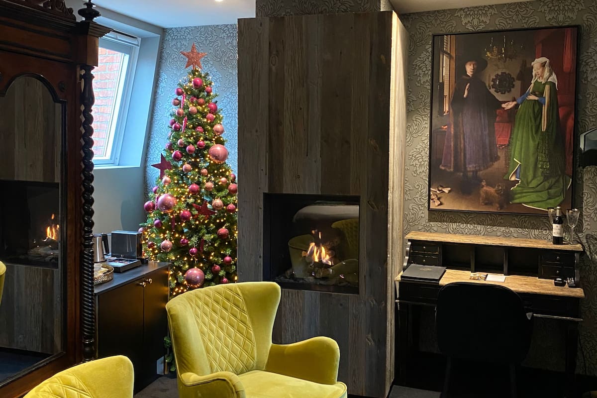 A cozy living room with a Christmas tree, a fireplace, and a painting on the wall.