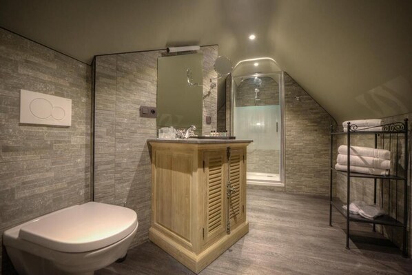 Un bagno con un mobile lavabo in legno, un water, uno spazio doccia in vetro e un portascopevoli.