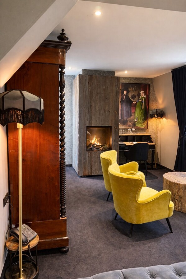 A modern living room with a fireplace, yellow chairs, a wooden cabinet, and a painting on the wall. - 't Hartje van Brugge (Bruges)