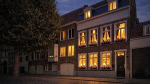 Un immeuble à plusieurs étages, avec des fenêtres illuminées et une lune dans le ciel.