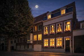A multi-story building with illuminated windows and a moon in the sky. - 't Hartje van Brugge (Bruges)