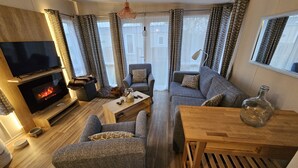 A cozy living room with a fireplace, comfortable seating, and a television. - Gemütliches Chalet im Ferienpark de Oase Renesse (Renesse)