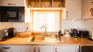 A kitchen with a built-in microwave, a sink, a coffee maker, and a toaster. - Gemütliches Chalet im Ferienpark de Oase Renesse (Renesse)