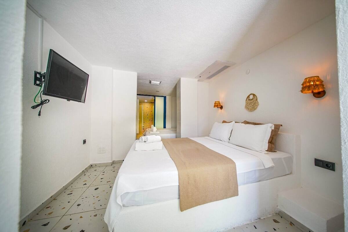 A hotel room with a bed, a television mounted on the wall, and a bathroom visible through an open door.