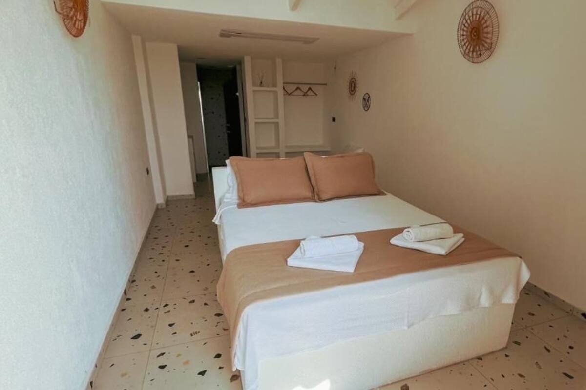 A hotel room with two beds, a door leading to a hallway, and a ceiling fan.