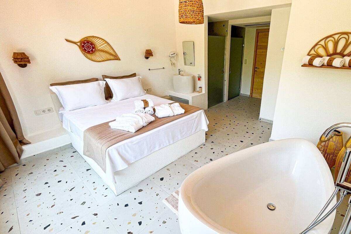 A hotel room with a bed, a large bathtub, and a shower.