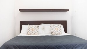 A neatly made bed with a dark quilted bedspread and two patterned pillows. - Casa Mila (Ostuni)