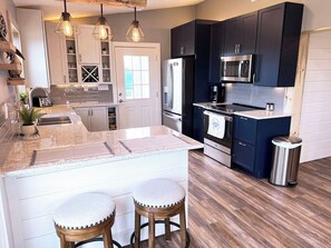 A modern kitchen with dark cabinets, stainless steel appliances, and a central island with stools.