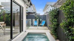 A modern house with a glass door leading to a patio area. - Beach Pad on Nautilus (Kingscliff)