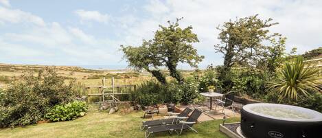 Um quintal com hidromassagem, cadeiras de descanso e vista para o campo.
