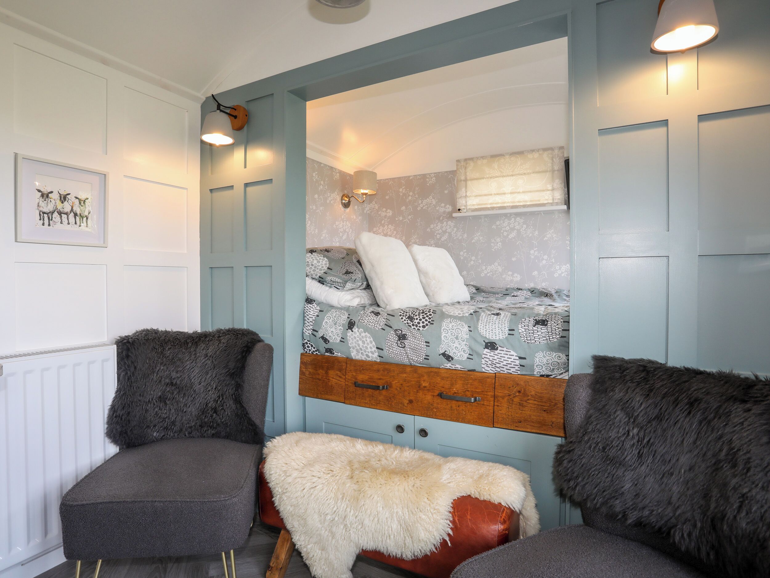 A room with a bed, two armchairs, a small stool, and a radiator.