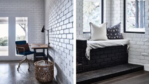 Una habitación con pared de ladrillo blanco, una mesa de madera, una silla azul y una cesta de mimbre.