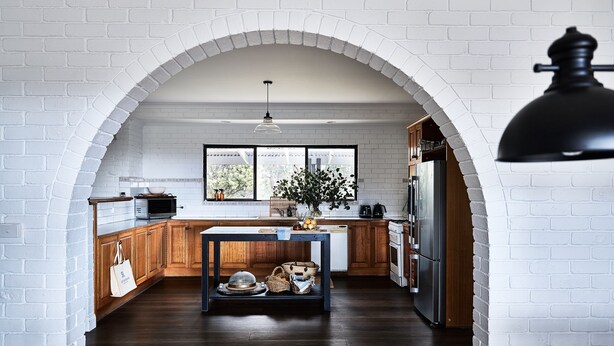 Una cocina con techo de ladrillo abovedado, armarios de madera, una isla central y vistas por una ventana.