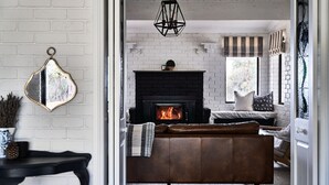Una sala de estar acogedora con chimenea, un sofá de cuero y un espejo en la pared.