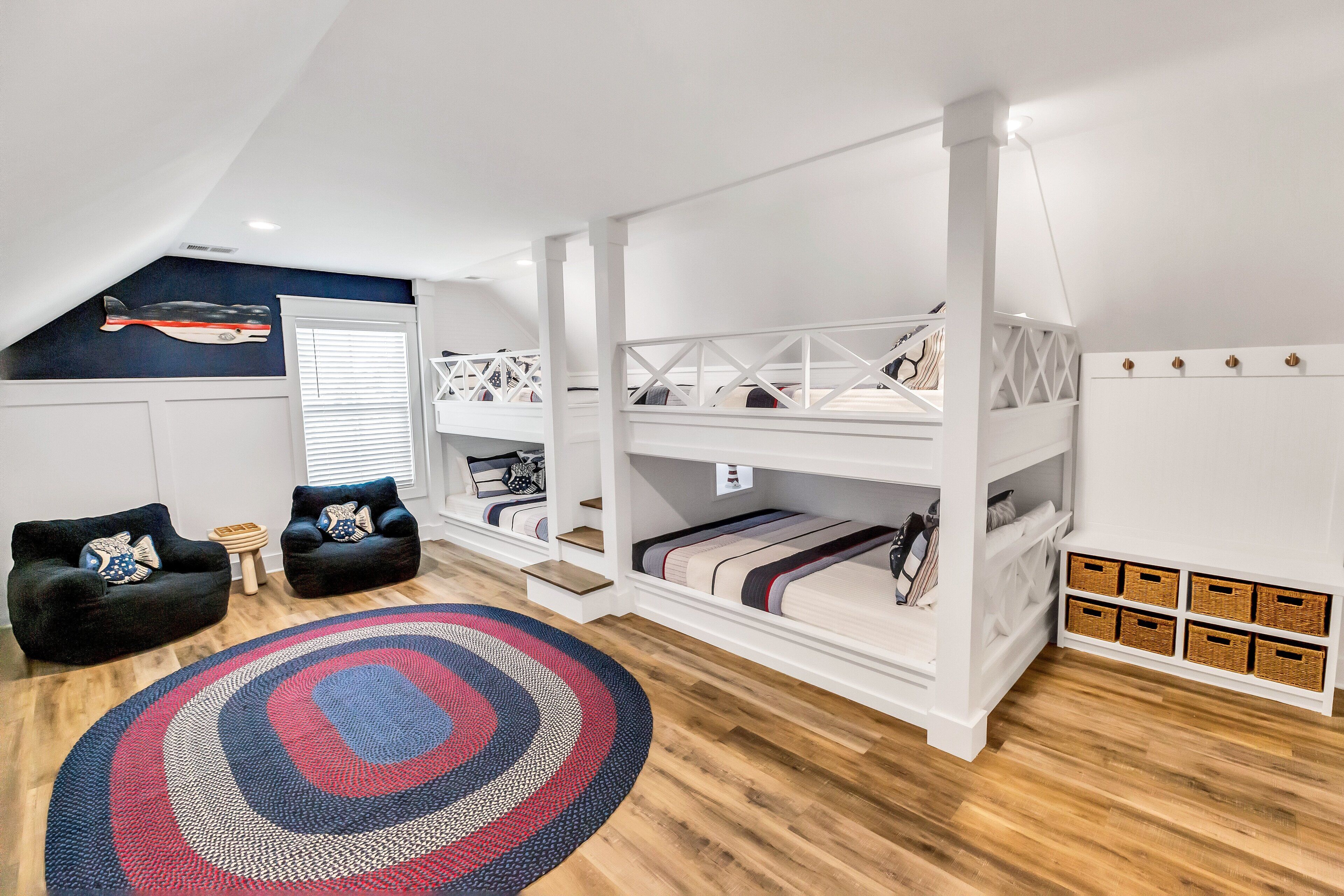 A loft bedroom with a bunk bed, two black sofas, a patterned rug, and storage baskets.
