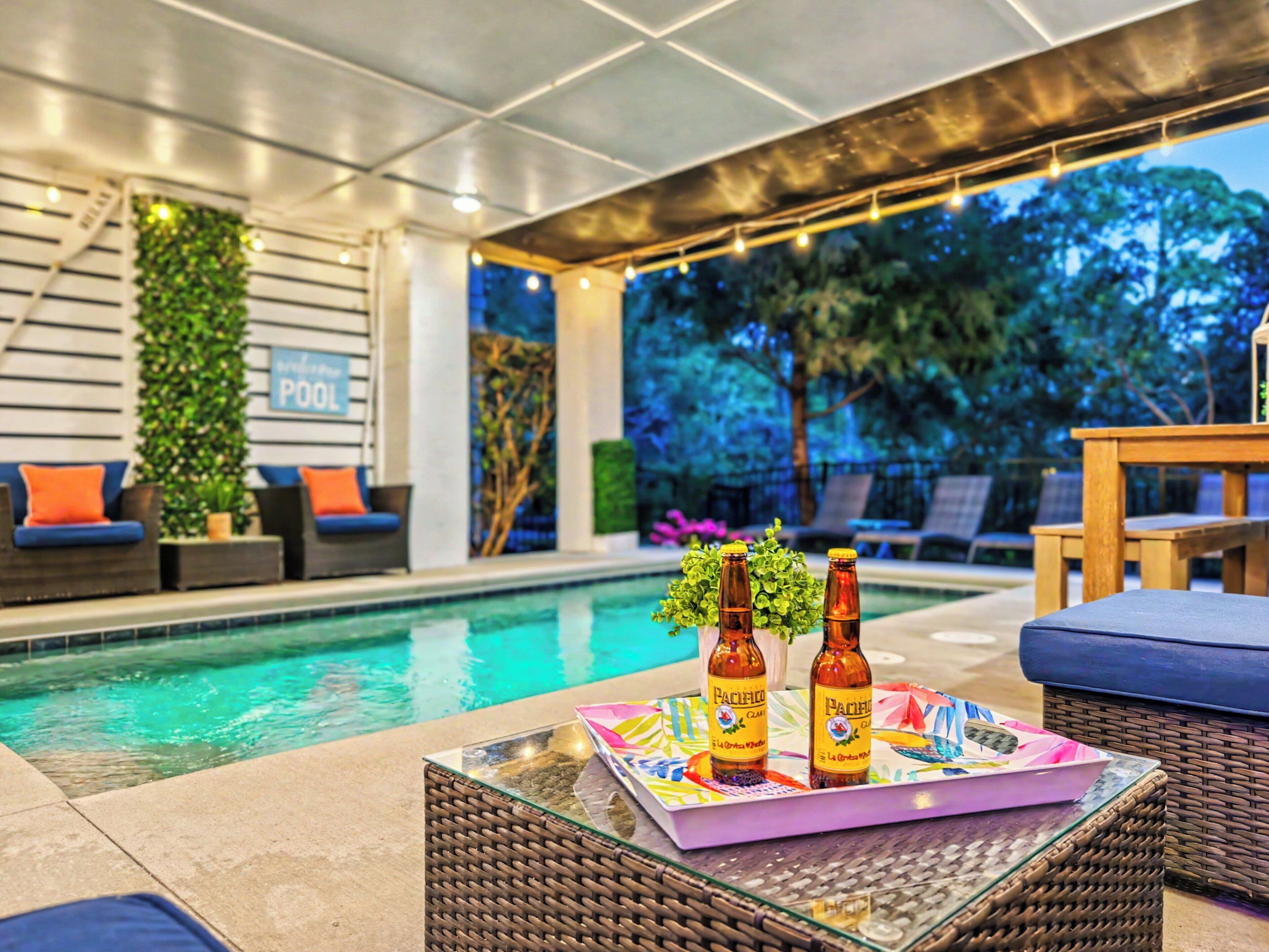 An indoor pool area with lounge chairs, a table with bottles, and a sign that reads 'POOL'.