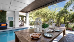 A poolside area with a wooden table, a sign reading "Welcome POOL", and outdoor seating. - 13SC Beach, Private Pool, 10 foot movie theater screen (Hilton Head Island)