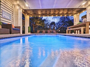 An indoor swimming pool with a covered area, lounge chairs, and a sign reading 'welcome to our POOL'.