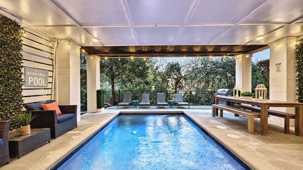 A pool area with a sign reading 'Welcome to our POOL,' surrounded by lounge chairs and a barbecue grill. - 13SC Beach, Private Pool, 10 foot movie theater screen (Hilton Head Island)