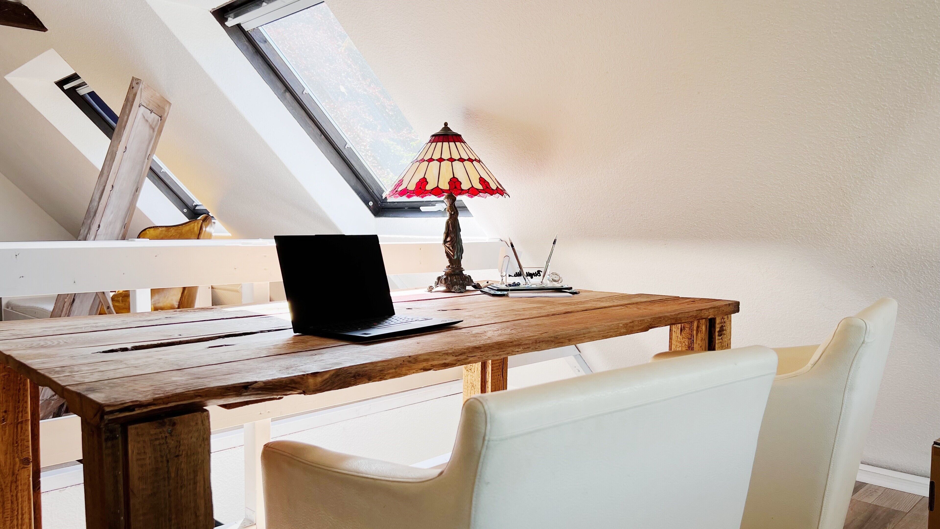 A wooden desk with a laptop, a lamp, and a notebook.