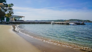 Une plage avec une petite maison et un bateau amarré près de l’eau.