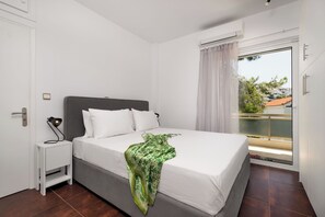 Une chambre à coucher avec un lit, une table de chevet, une fenêtre avec des rideaux et une vue sur l’extérieur.