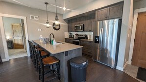 Una cocina moderna con una isla central, electrodomésticos de acero inoxidable y taburetes de madera.