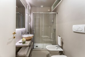 A compact bathroom with a glass-enclosed shower, a wooden bowl sink, and a white pedestal sink. - SAN VIO PALACE LUXURY APARTMENTS (Venice)