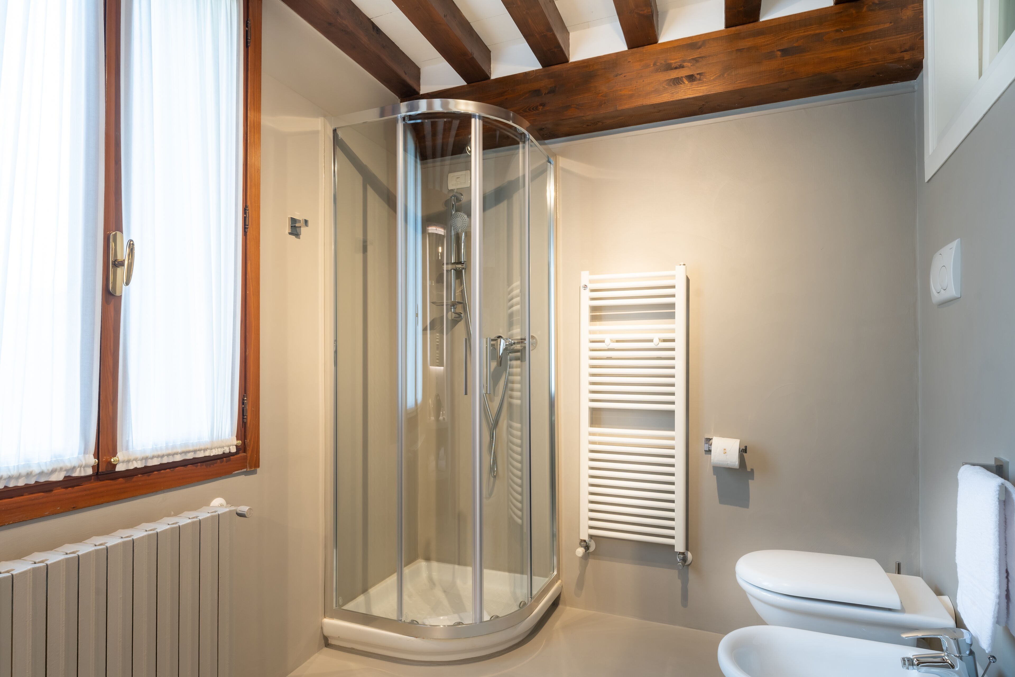 Un baño moderno con cabina de ducha de vidrio, inodoro y radiador.