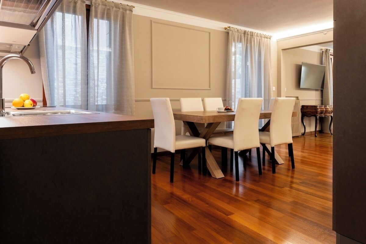 Una cocina moderna con encimera de madera, un fregadero y una zona de comedor con mesa y sillas.