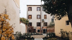 A courtyard with a central pathway, surrounded by buildings with multiple windows and a brick wall. - SAN VIO PALACE LUXURY APARTMENTS (Venice)
