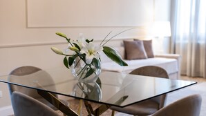 A modern dining area with a glass table, chairs, and a vase of white flowers. - SAN VIO PALACE LUXURY APARTMENTS (Venice)