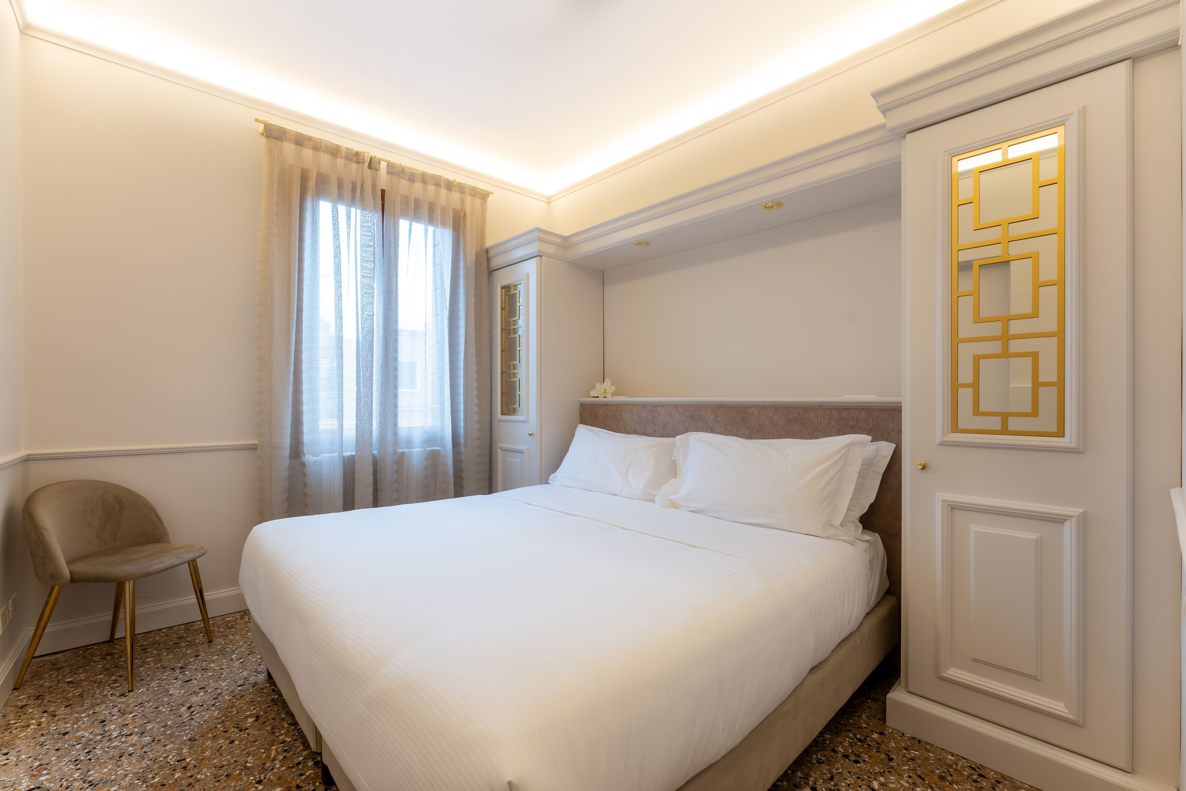 Una habitación de hotel con una cama grande, una silla y una puerta con un panel decorativo.