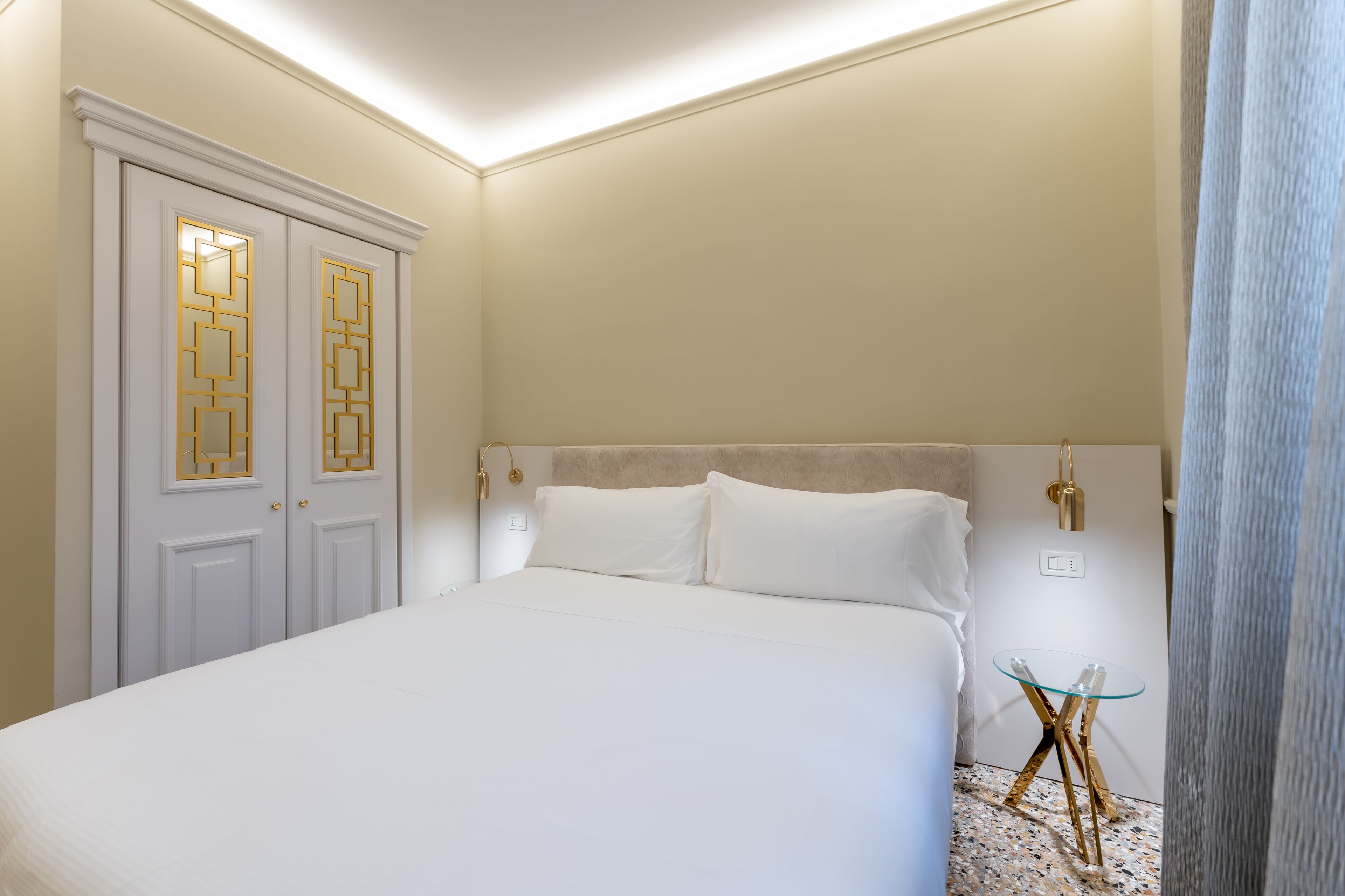 Een slaapkamer met een groot bed, een nachtkastje en een garderobe met decoratieve deuren.