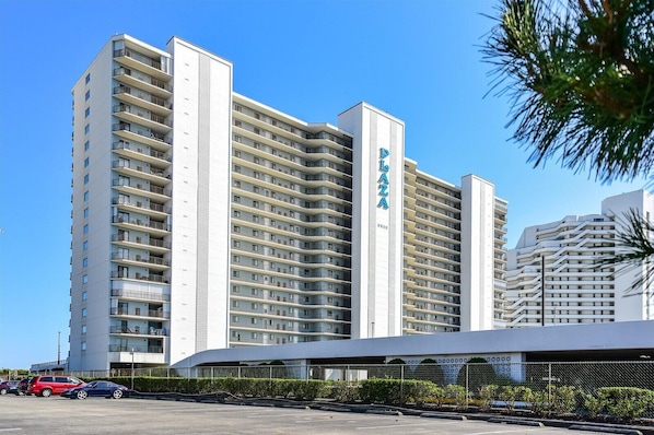 Un hotel de gran altura con varios balcones, un letrero destacado que dice 'Palo Alto' y un área de estacionamiento al frente.