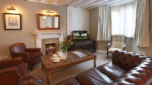 A living room with a fireplace, leather furniture, a television, and a large window with curtains.