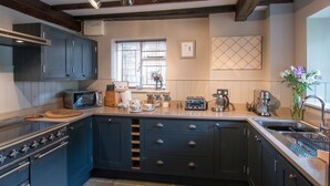 A kitchen with dark blue cabinets, a built-in oven, a microwave, and a coffee maker.