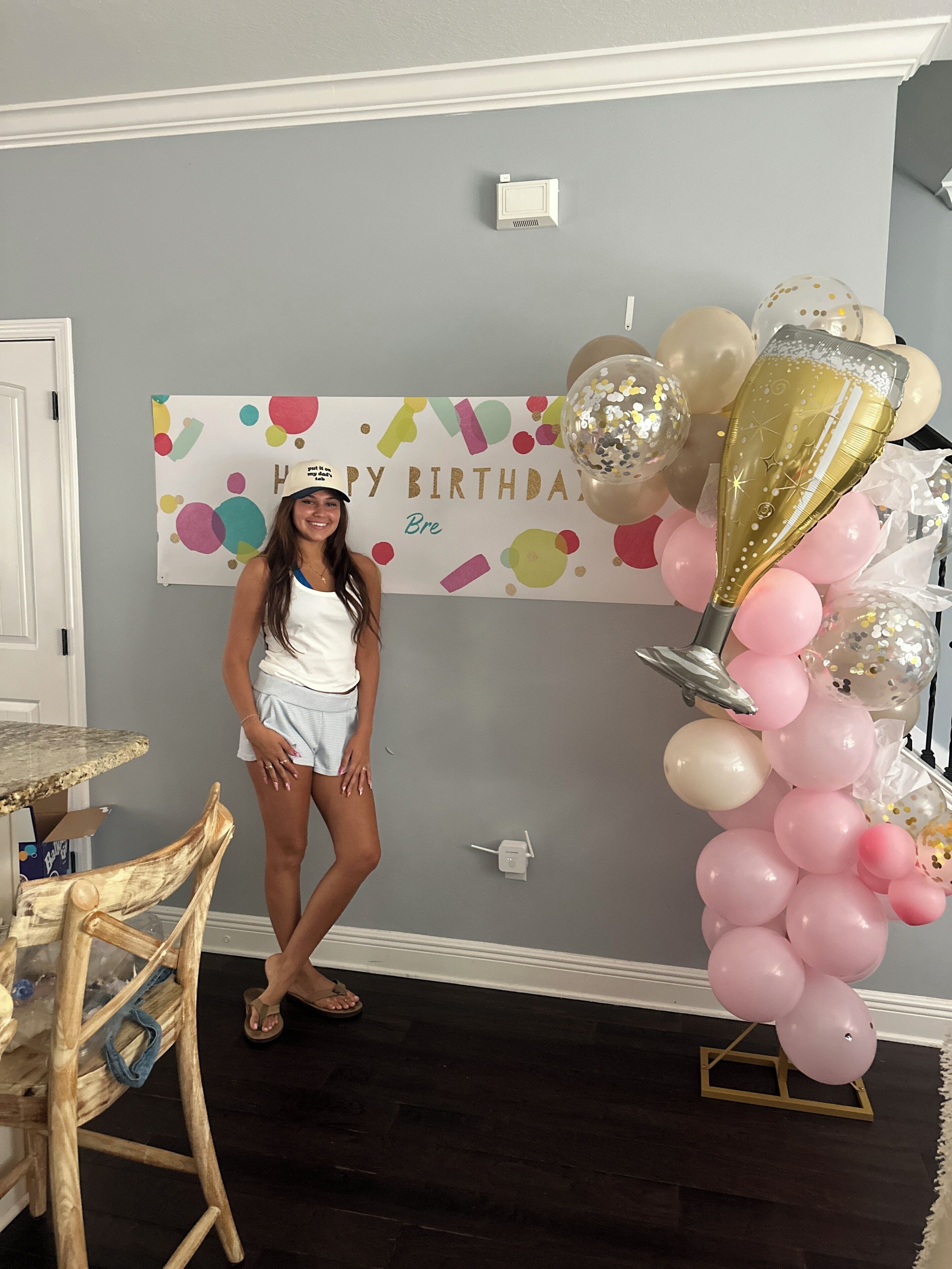 Una habitación decorada con un cartel de cumpleaños, globos y una silla.