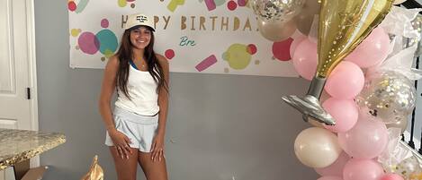 Una habitación decorada con un cartel de cumpleaños, globos y una silla.