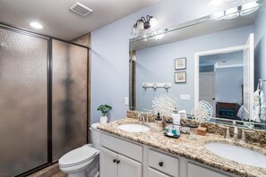 A bathroom with two sinks, a toilet, and a shower.