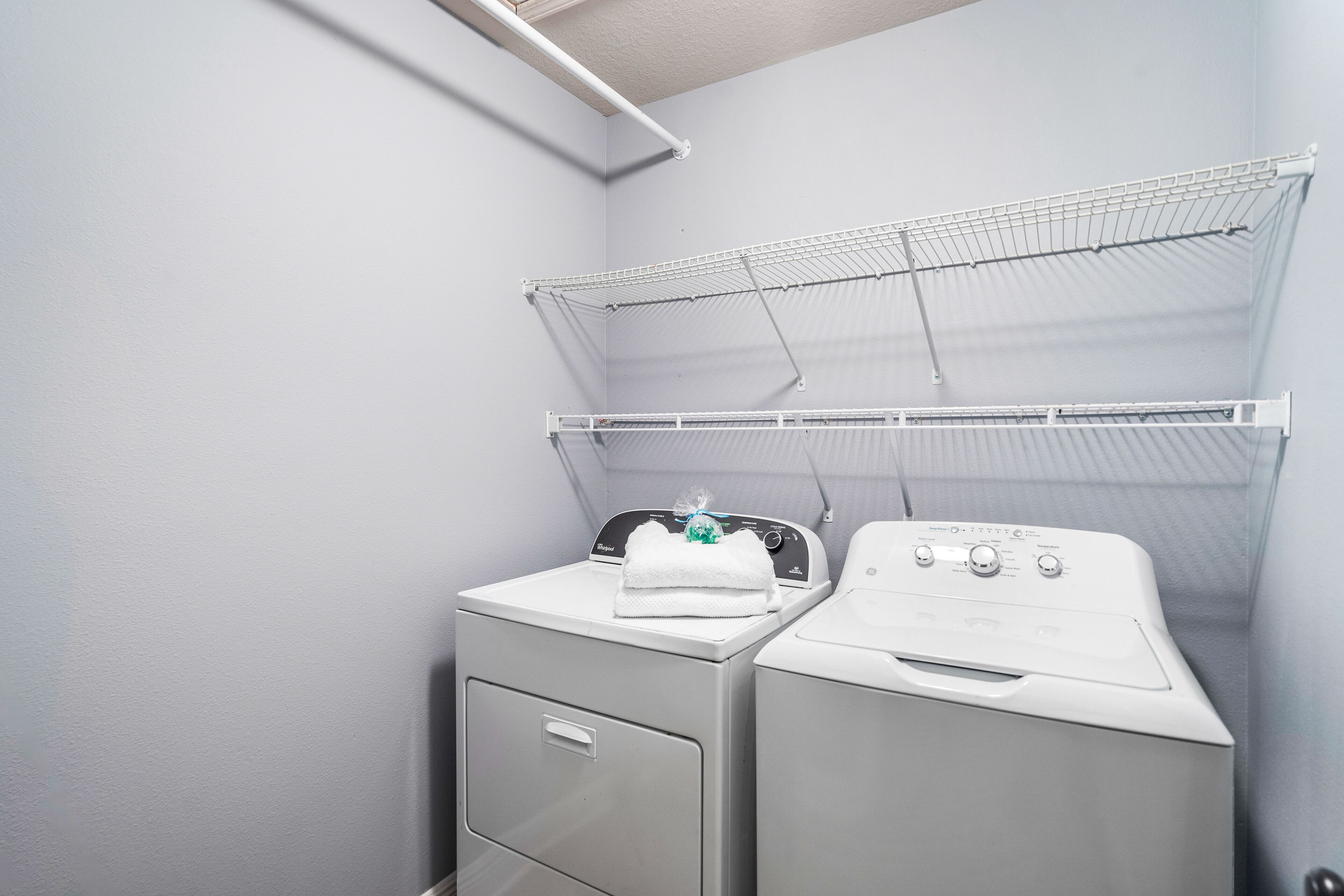 A laundry area with two washing machines and a drying rack.