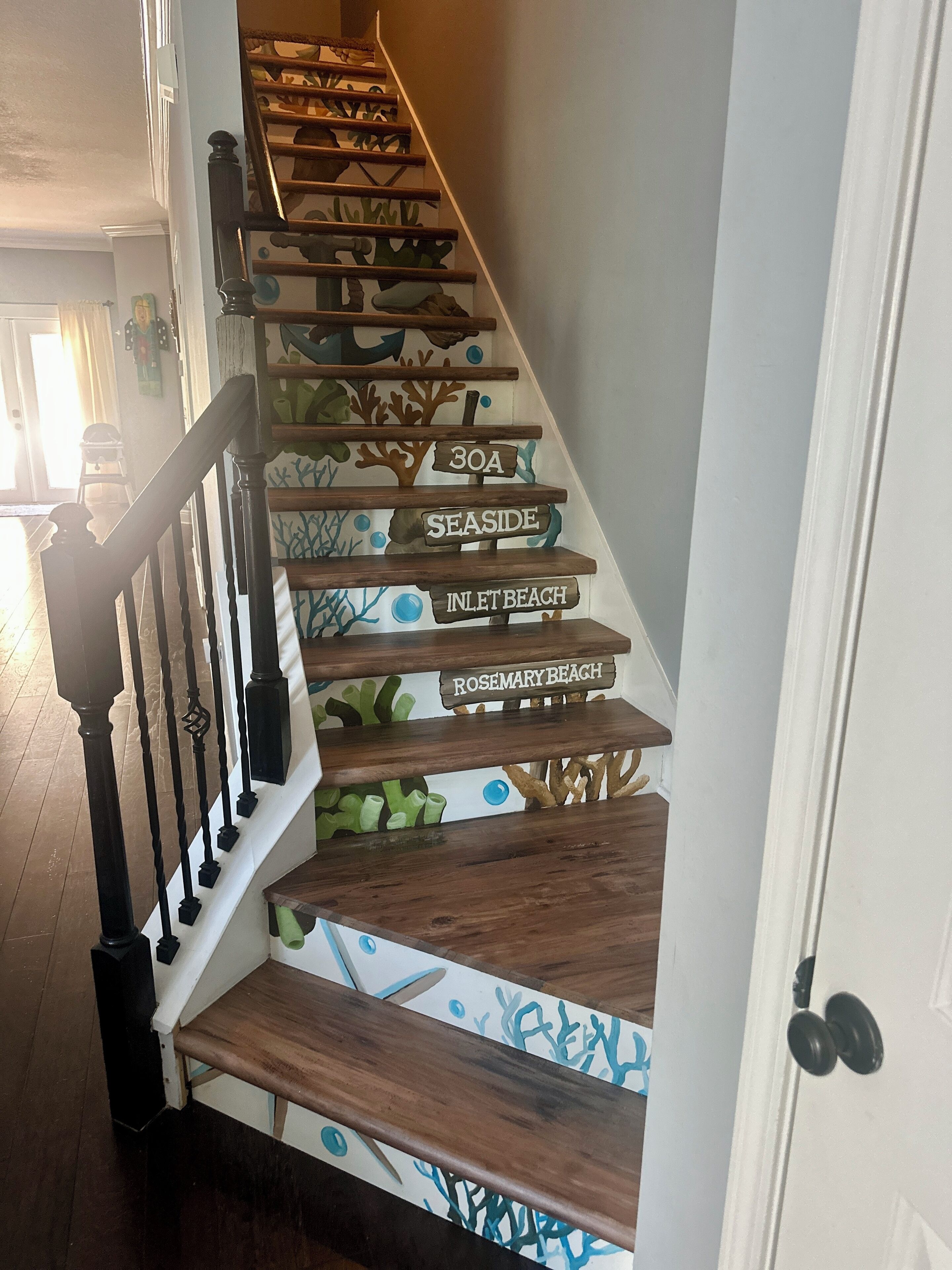 A staircase with wooden steps and a railing. Each step has a nameplate with a beach name.