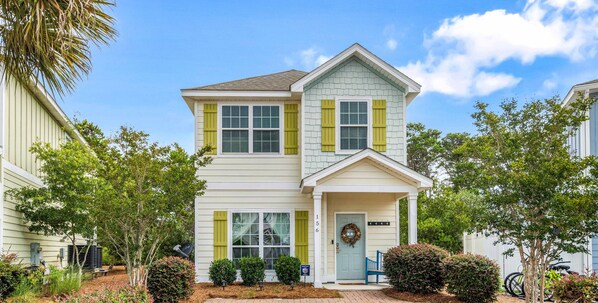 A two-story house with a front porch, a mailbox, and a wreath on the door.