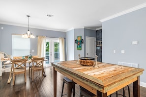Enjoy family meals and gatherings in this dining area with a large table and matching chairs, a modern chandelier, and a view of the outdoors.