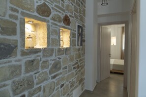Stunning hallway with a rustic stone wall and three decorative niches, leading to a cozy space with a comfortable bed.