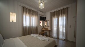 Ein Hotelzimmer mit einem großen Bett, einem Schreibtisch, einem Sessel, einem Fernseher und Vorhängen.