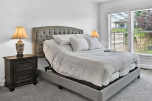 A bedroom with a bed, two nightstands, and a window with blinds.