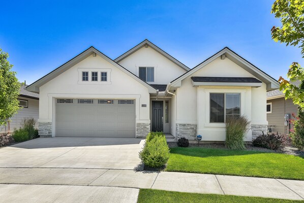 A two-story house with a garage, a front lawn, and a small garden area.