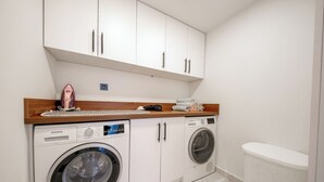 A laundry room with two washing machines, a dryer, and a wooden countertop with various items. - Misty Mountain Luxury Villa Fethiye, Uzumlu (Fethiye)